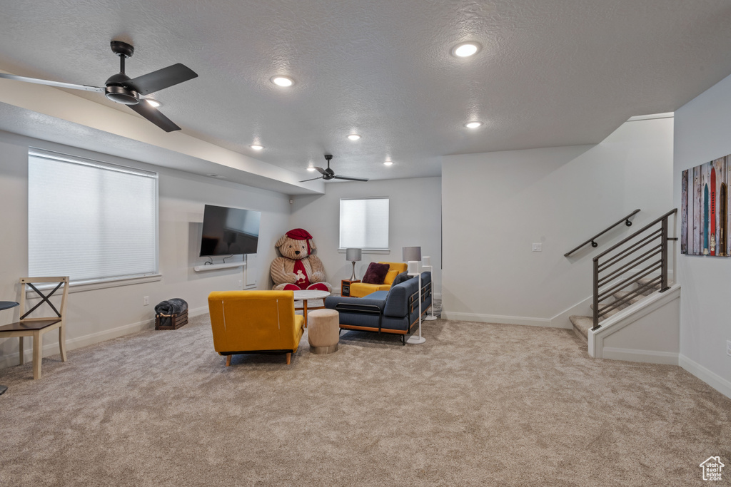 Living room featuring light colored carpet, a textured ceiling, and ceiling fan