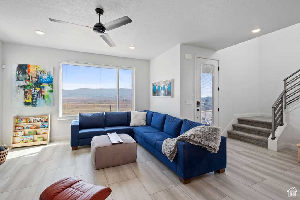 Living room featuring a textured ceiling, light hardwood / wood-style flooring, a mountain view, and ceiling fan