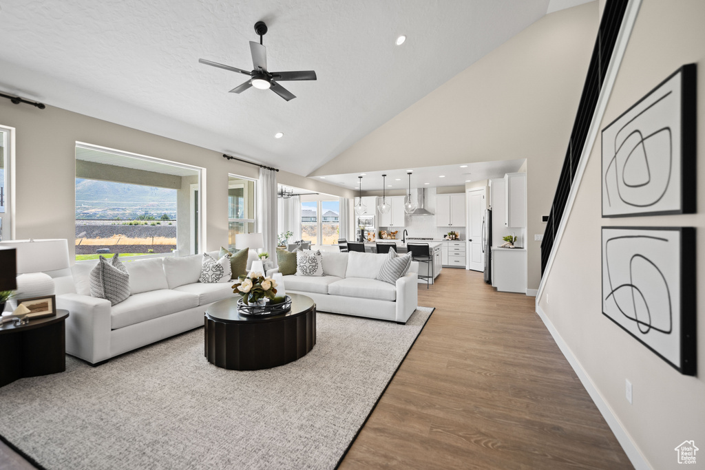 Living room with wood-type flooring, high vaulted ceiling, and ceiling fan