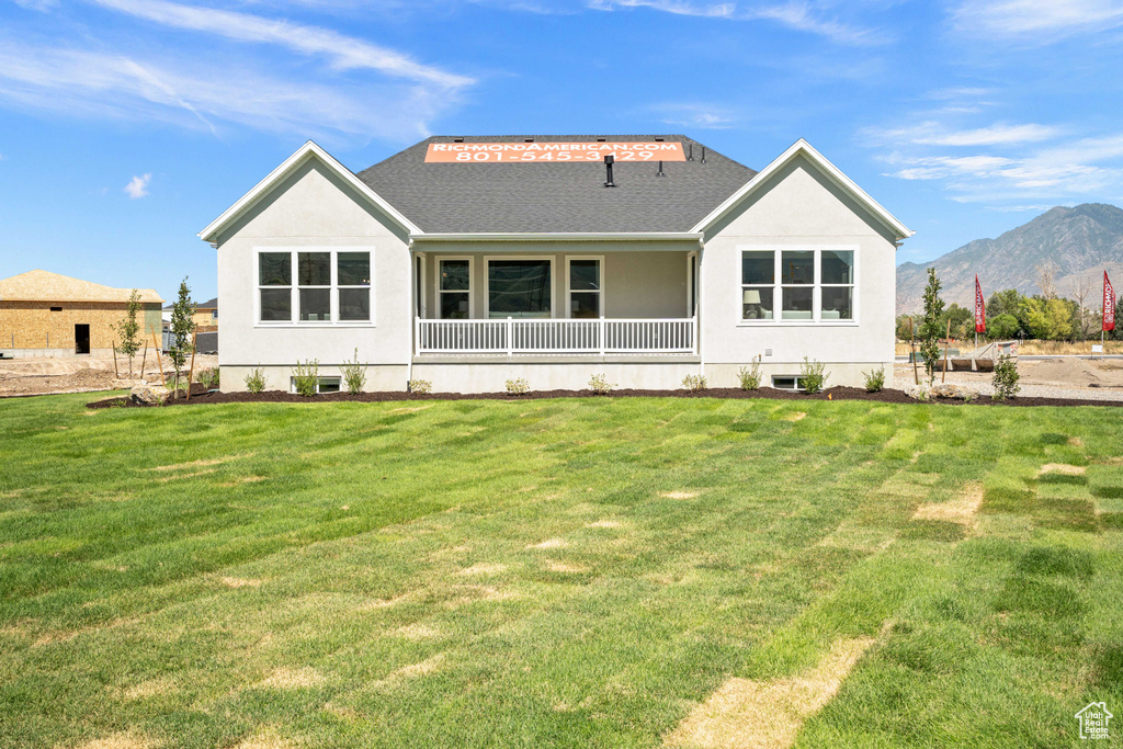 Rear view of property with a mountain view and a yard