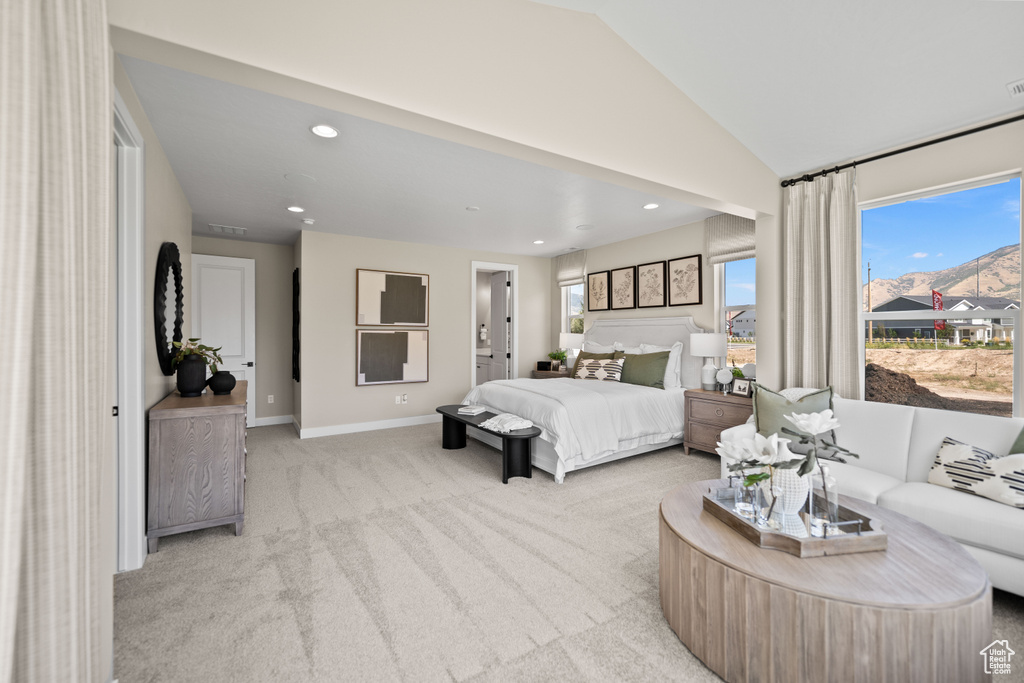 Bedroom with light colored carpet, vaulted ceiling, and connected bathroom