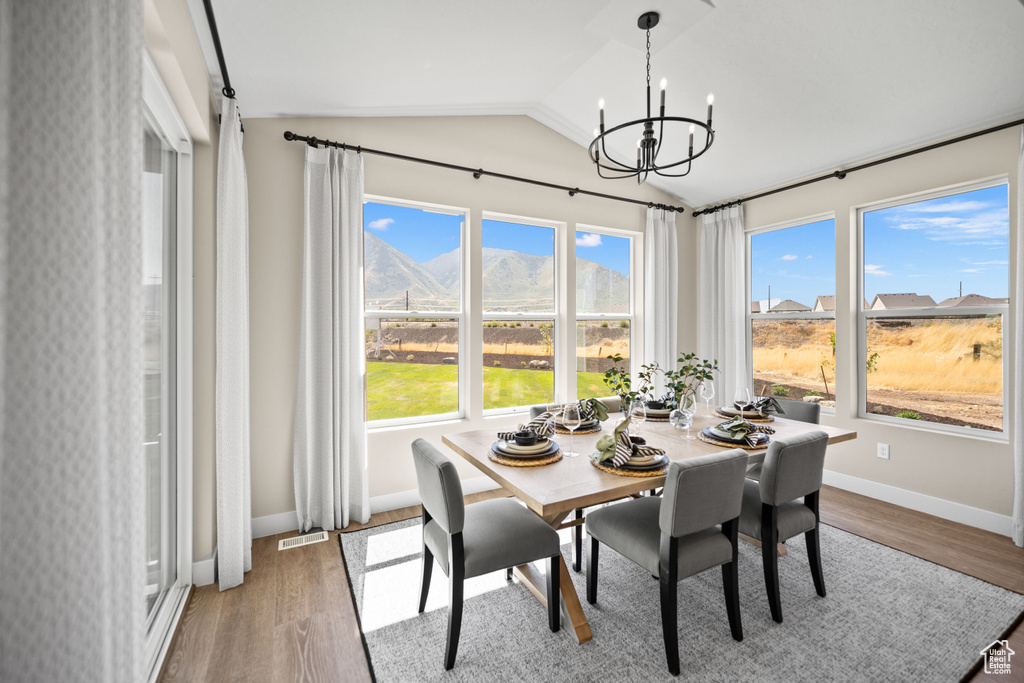 Dining space featuring a notable chandelier, lofted ceiling, a mountain view, and hardwood / wood-style flooring