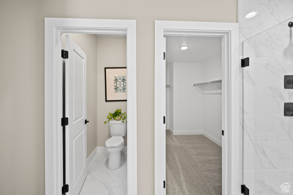 Bathroom featuring a tile shower and toilet