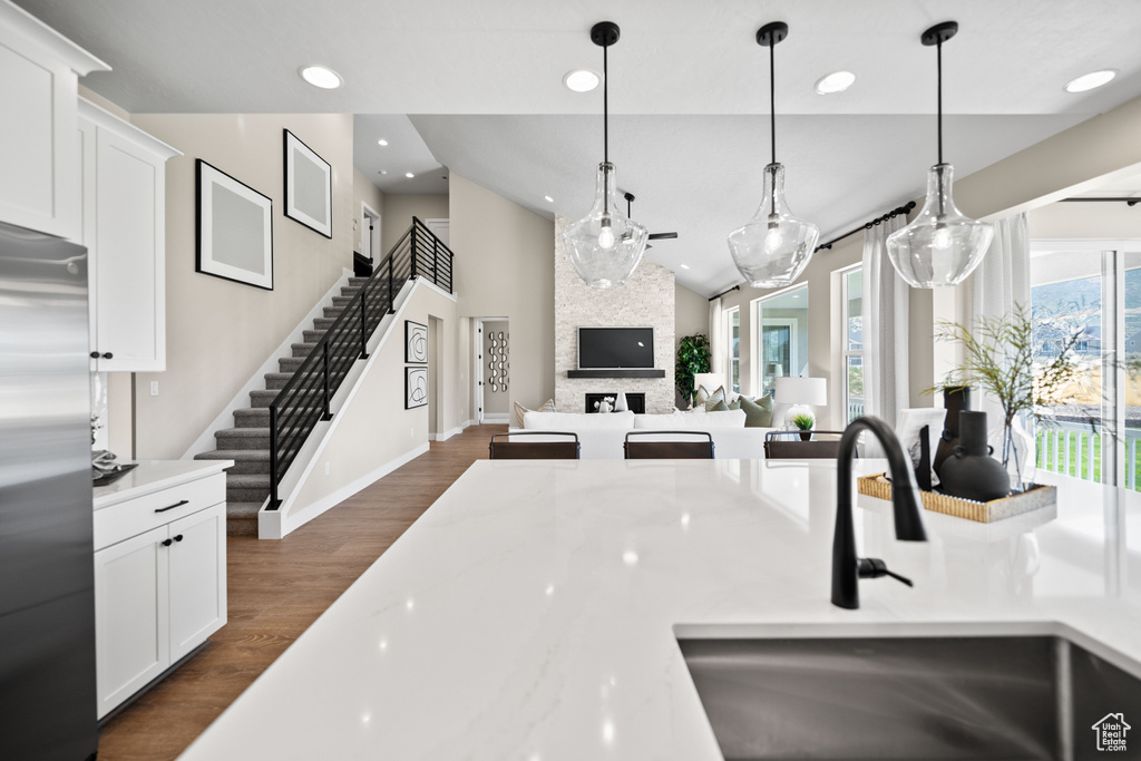 Kitchen featuring light stone counters, stainless steel fridge, dark hardwood / wood-style flooring, a fireplace, and white cabinetry