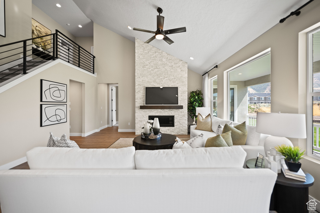 Living room featuring high vaulted ceiling, ceiling fan, a fireplace, and hardwood / wood-style floors