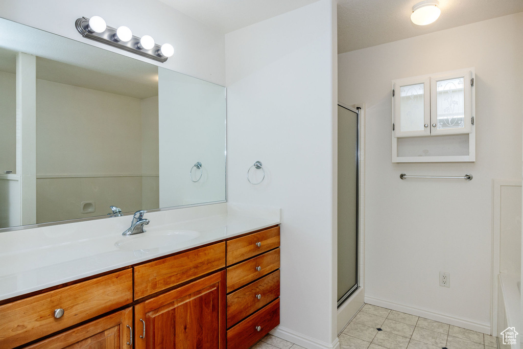 Bathroom featuring vanity, a shower with shower door, and tile patterned floors