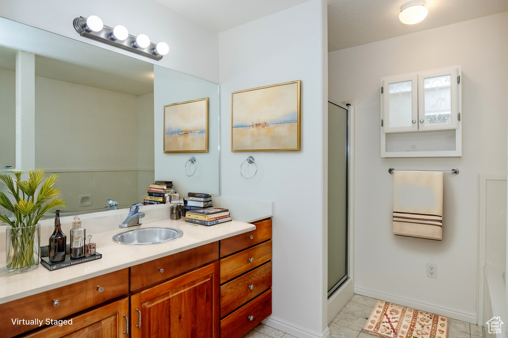 Bathroom featuring tile patterned floors, vanity, and walk in shower