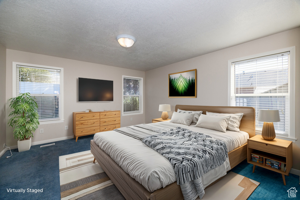 Bedroom featuring a textured ceiling and dark colored carpet