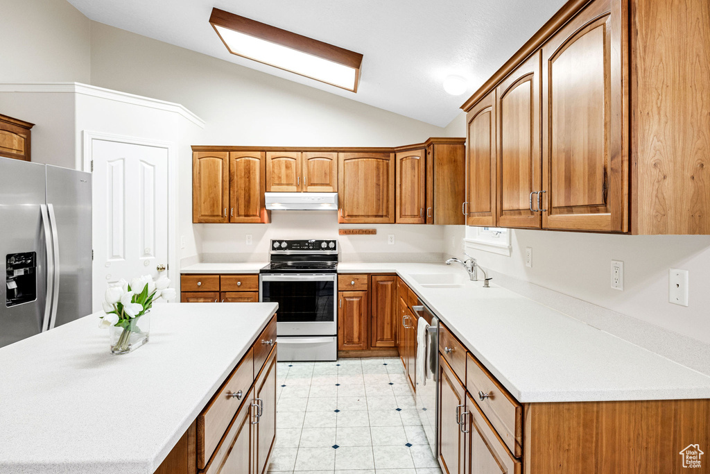 Kitchen featuring sink, stainless steel appliances, vaulted ceiling, and light tile patterned flooring