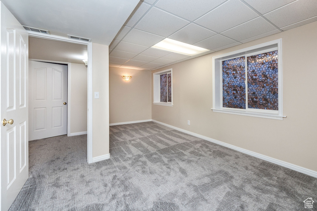 Basement with a paneled ceiling and light colored carpet