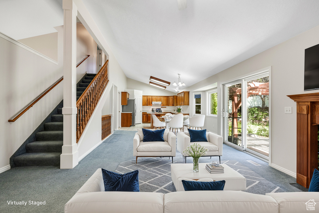 Living room featuring lofted ceiling, a notable chandelier, and carpet flooring