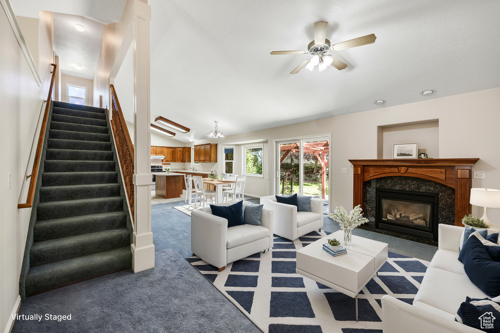 Living room featuring a premium fireplace, light carpet, ceiling fan, and lofted ceiling