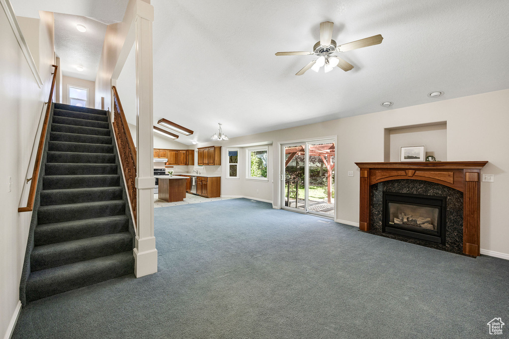 Unfurnished living room with a premium fireplace, lofted ceiling, ceiling fan, and carpet flooring