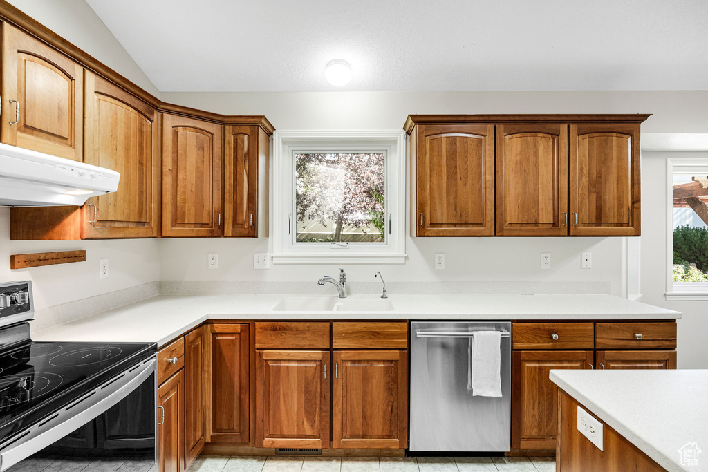 Kitchen featuring appliances with stainless steel finishes, vaulted ceiling, a wealth of natural light, and sink