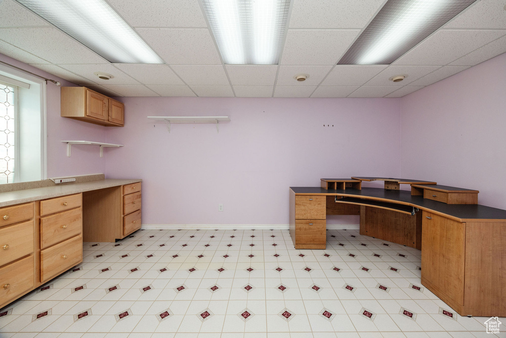 Office featuring a drop ceiling and built in desk