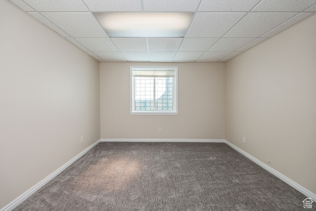 Carpeted spare room featuring a drop ceiling