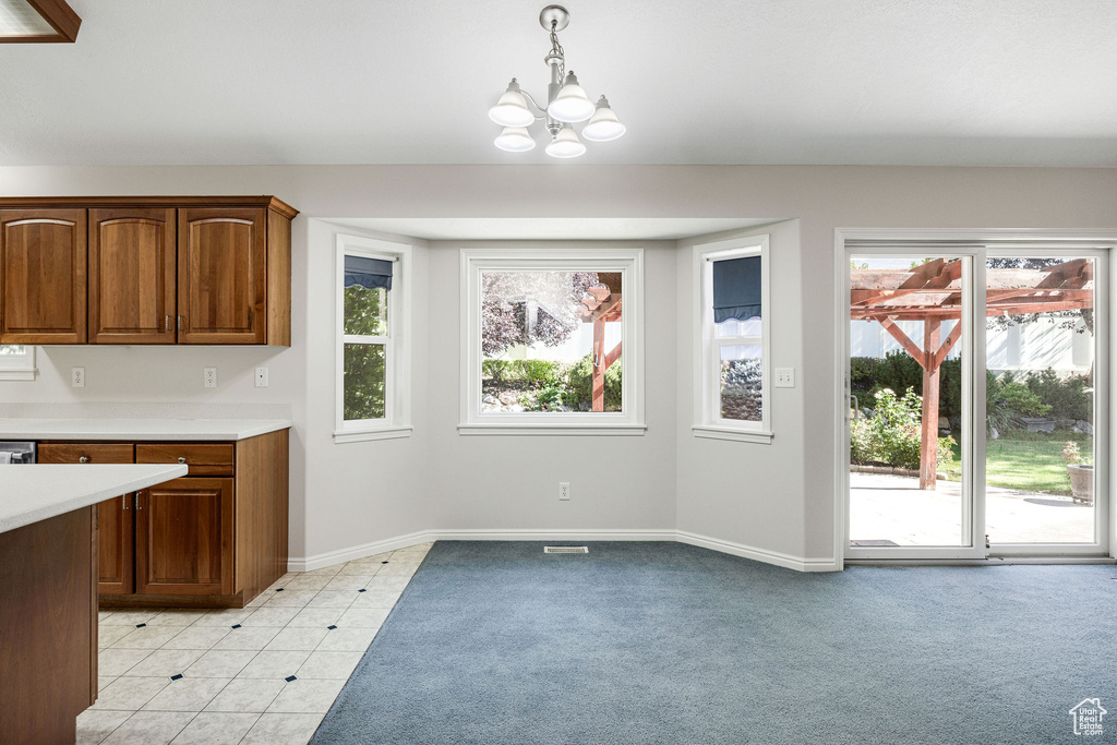 Unfurnished dining area with light colored carpet and an inviting chandelier