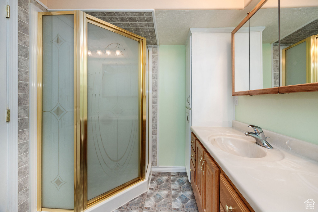 Bathroom featuring a shower with door, vanity, and a textured ceiling