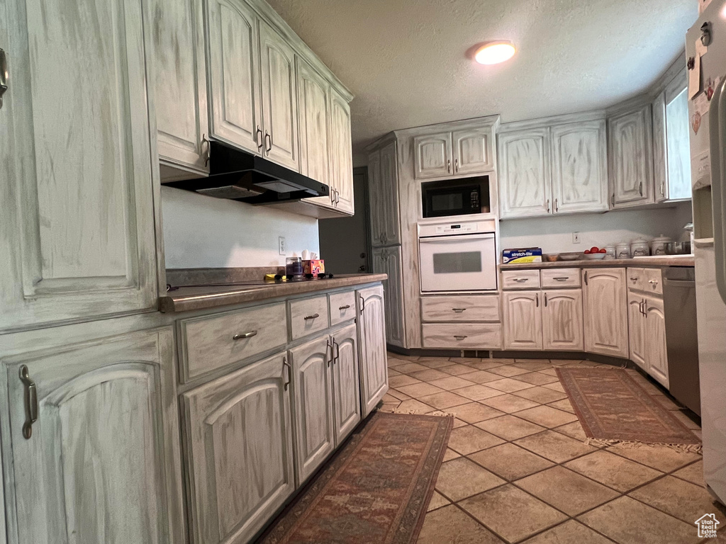 Kitchen featuring black appliances, light tile patterned floors, and a textured ceiling