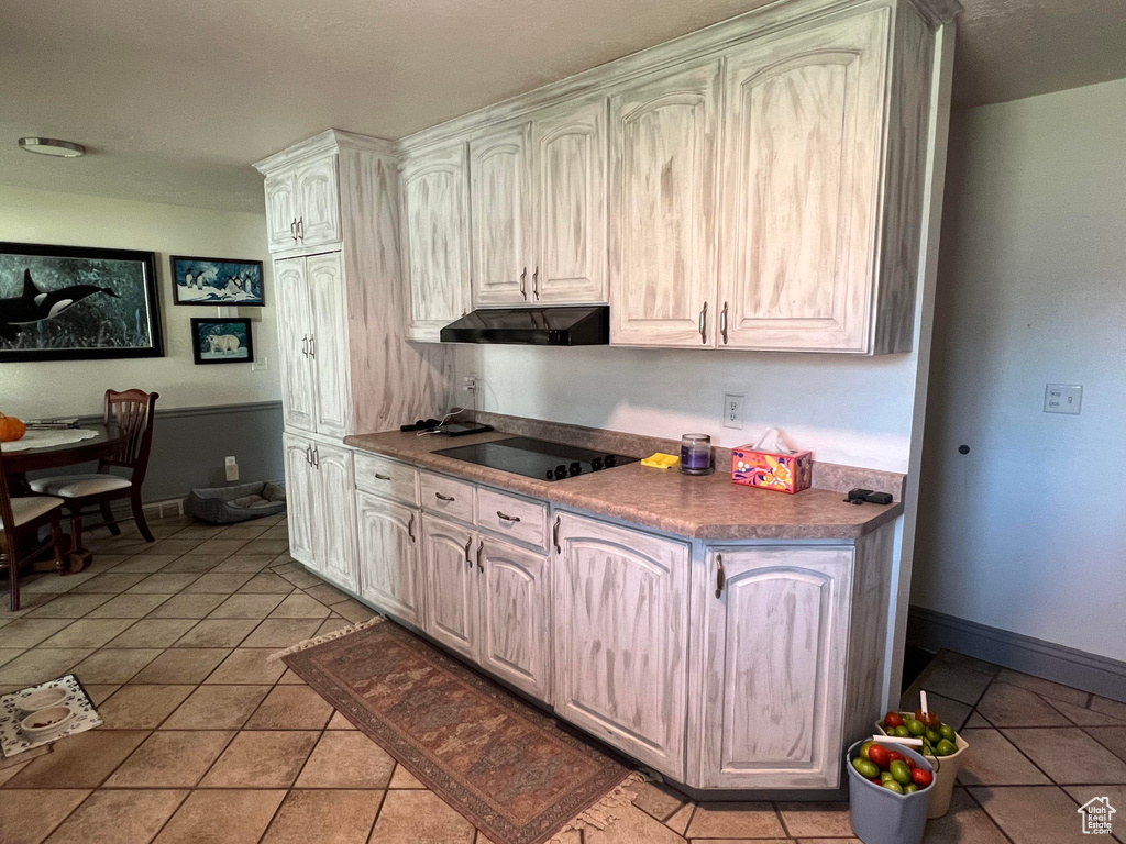 Kitchen with light tile patterned flooring and black electric cooktop