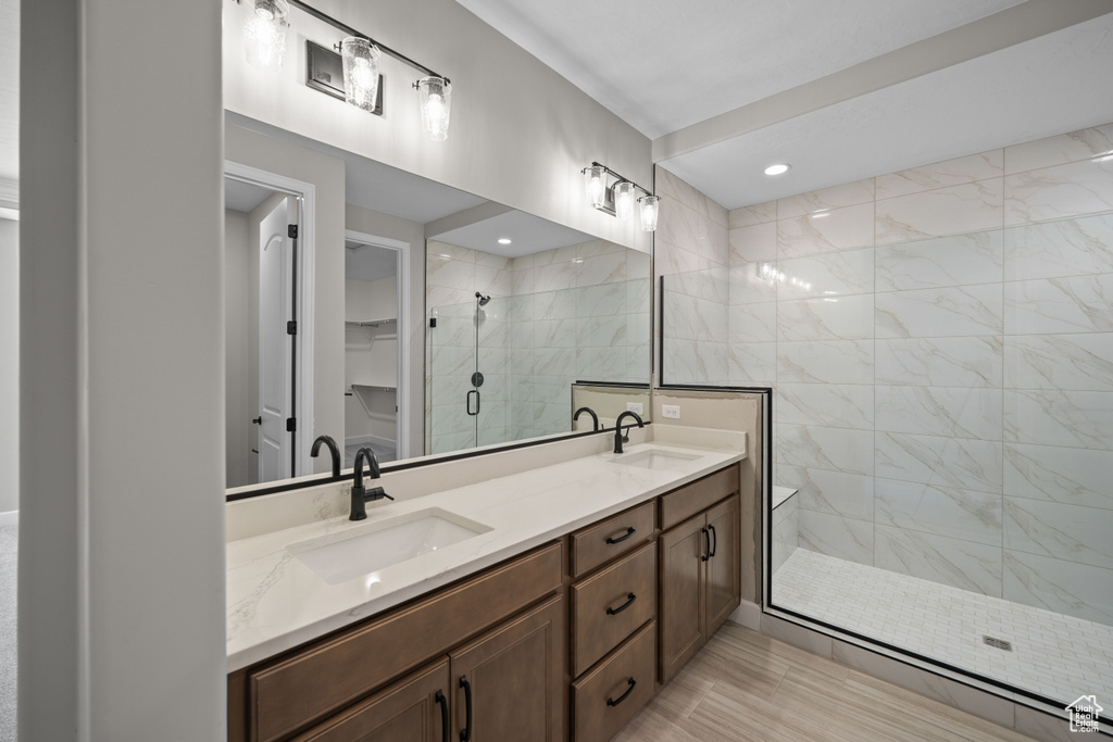 Bathroom with wood-type flooring, a tile shower, and vanity