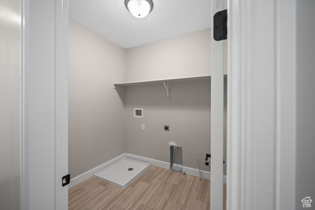 Laundry room with washer hookup, hardwood / wood-style flooring, a textured ceiling, and hookup for an electric dryer