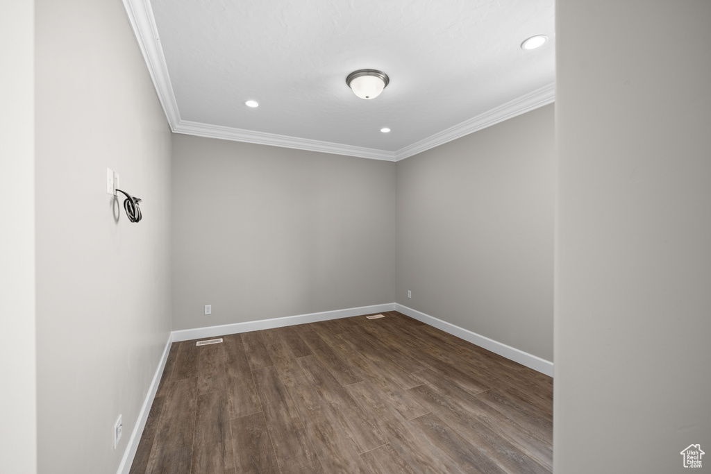 Unfurnished room with crown molding and dark wood-type flooring