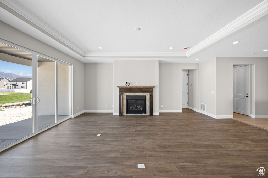 Unfurnished living room with a raised ceiling and dark hardwood / wood-style flooring