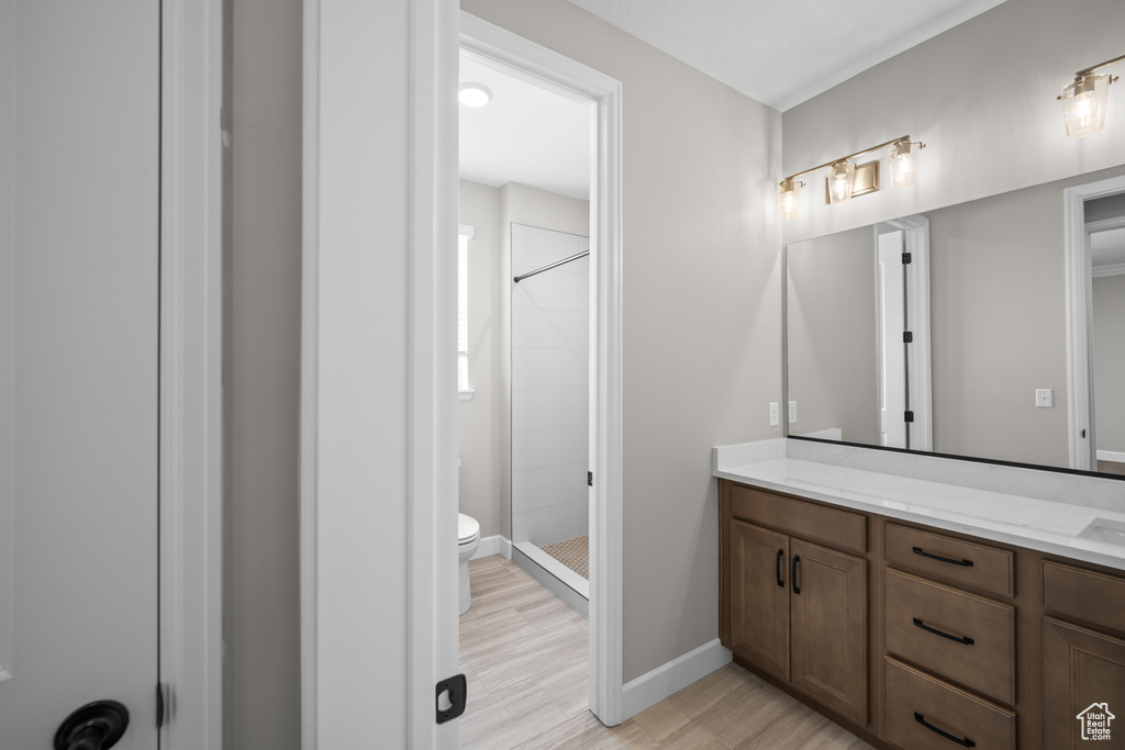 Bathroom featuring walk in shower, vanity, toilet, and wood-type flooring