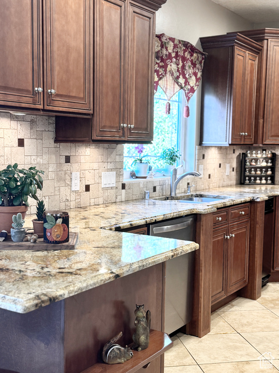 Kitchen with sink, light stone counters, dishwasher, backsplash, and light tile patterned floors