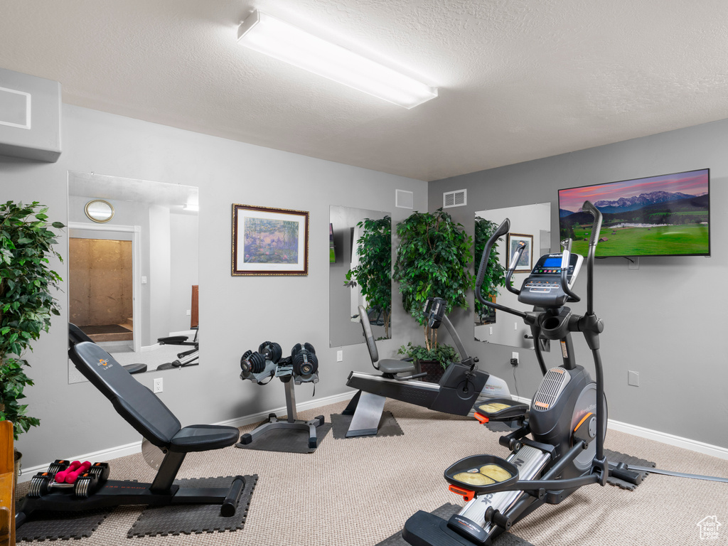 Exercise area featuring carpet flooring and a textured ceiling