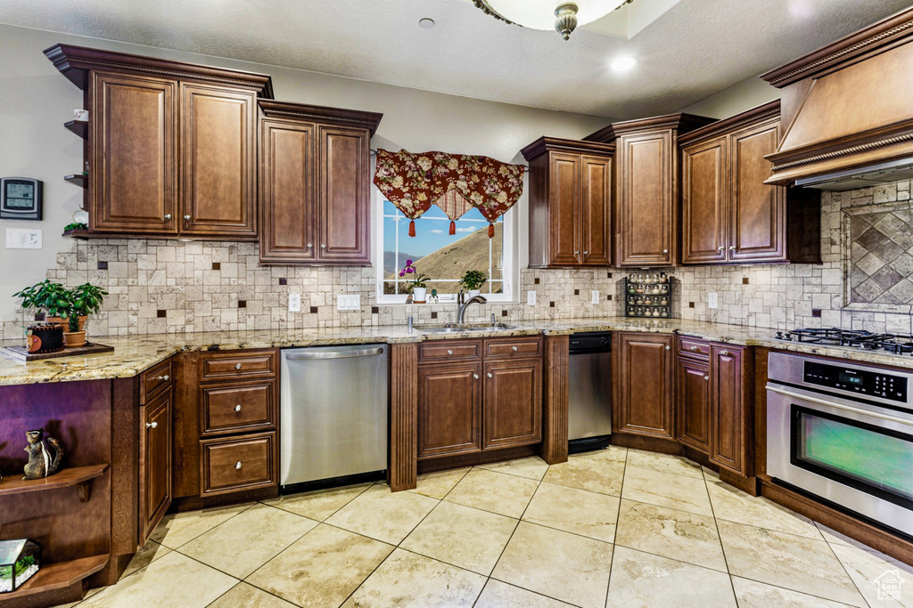 Kitchen with stainless steel appliances, tasteful backsplash, sink, and custom exhaust hood