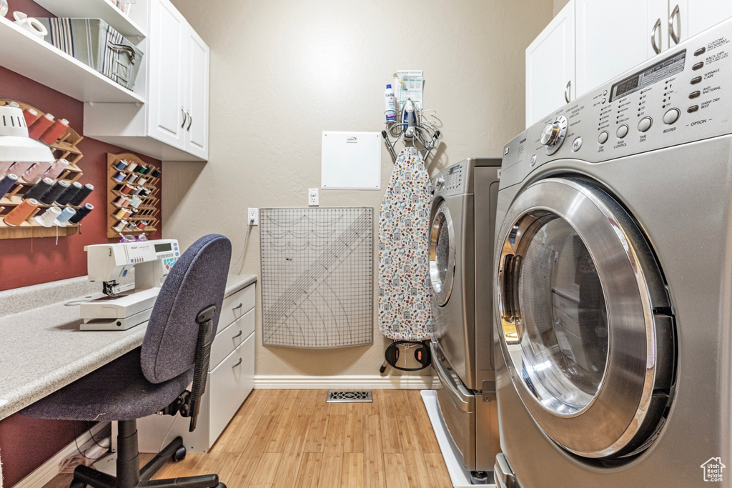 Washroom with light hardwood / wood-style floors, cabinets, and washing machine and clothes dryer