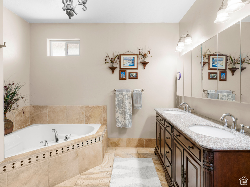 Bathroom with tile patterned floors, a relaxing tiled tub, and vanity