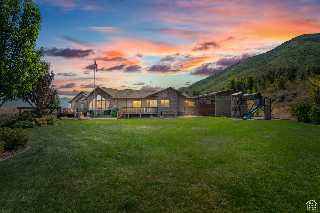 Yard at dusk with a playground and a deck with mountain view