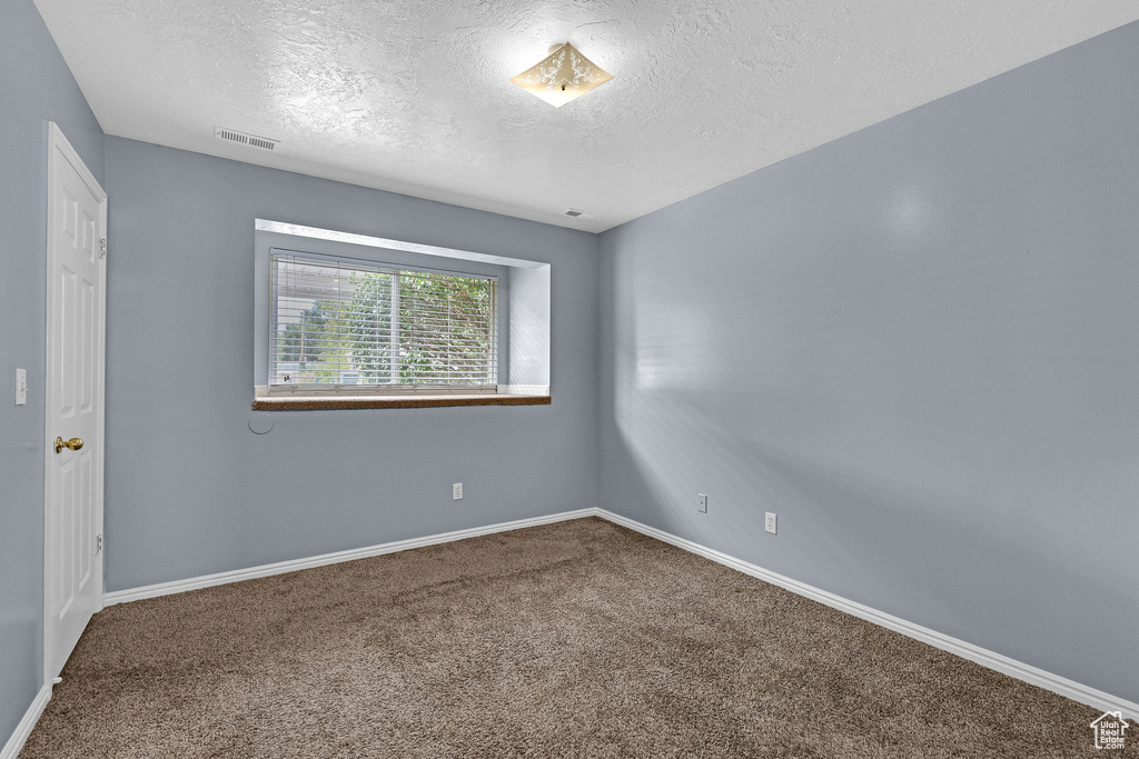 Carpeted spare room featuring a textured ceiling