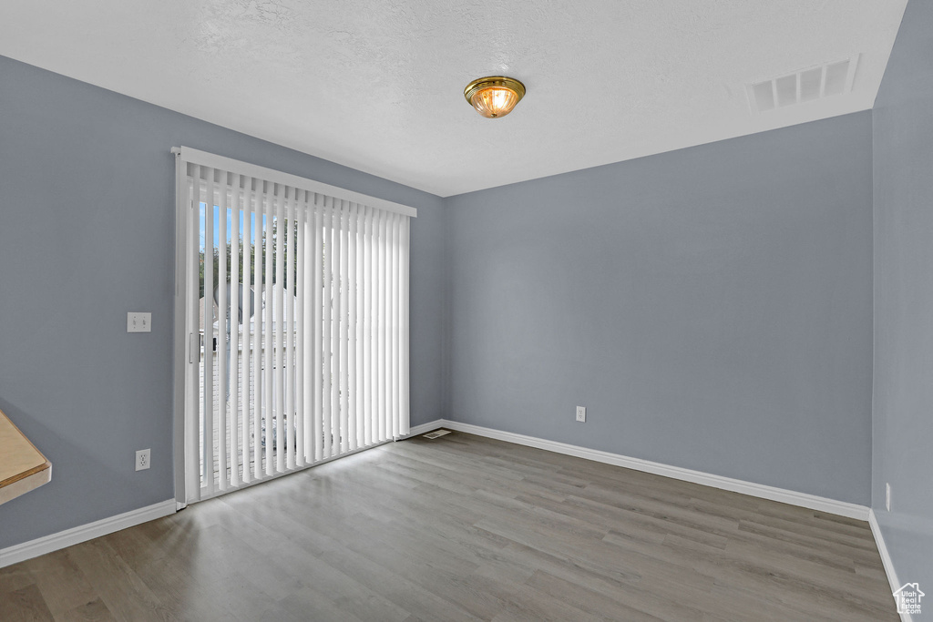 Unfurnished room with hardwood / wood-style floors and a textured ceiling