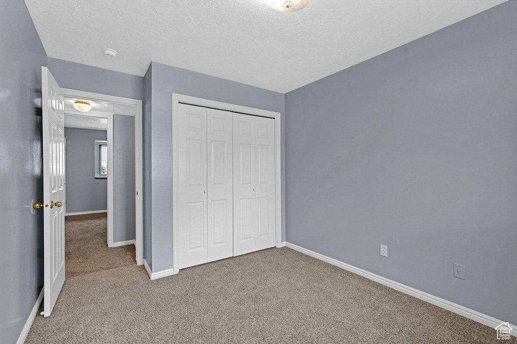 Unfurnished bedroom with a textured ceiling, a closet, and carpet flooring