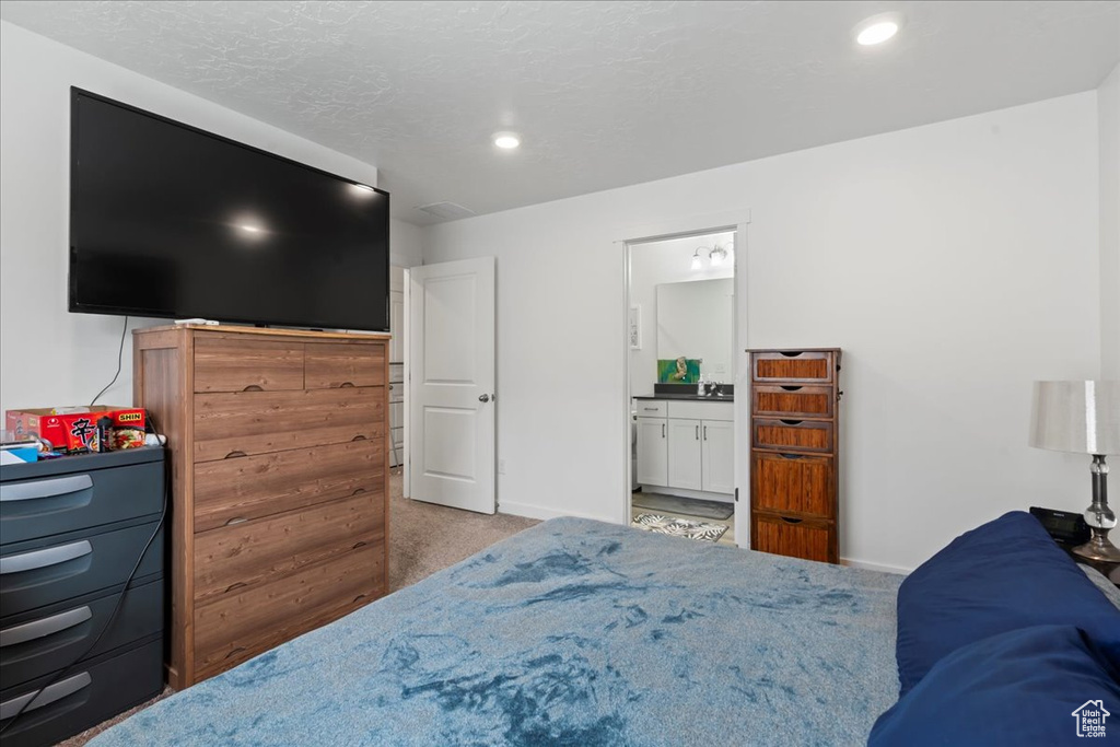 Bedroom featuring light carpet and ensuite bath