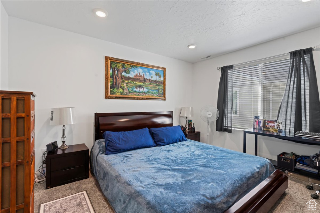 Bedroom featuring a textured ceiling and light colored carpet