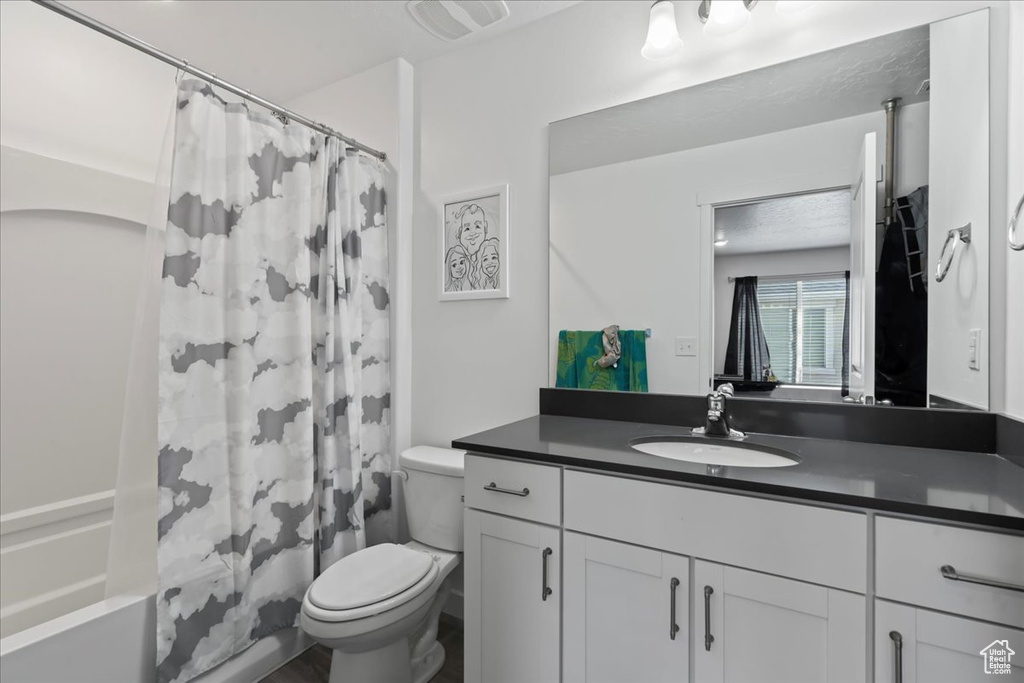 Full bathroom featuring shower / bathtub combination with curtain, vanity, and toilet