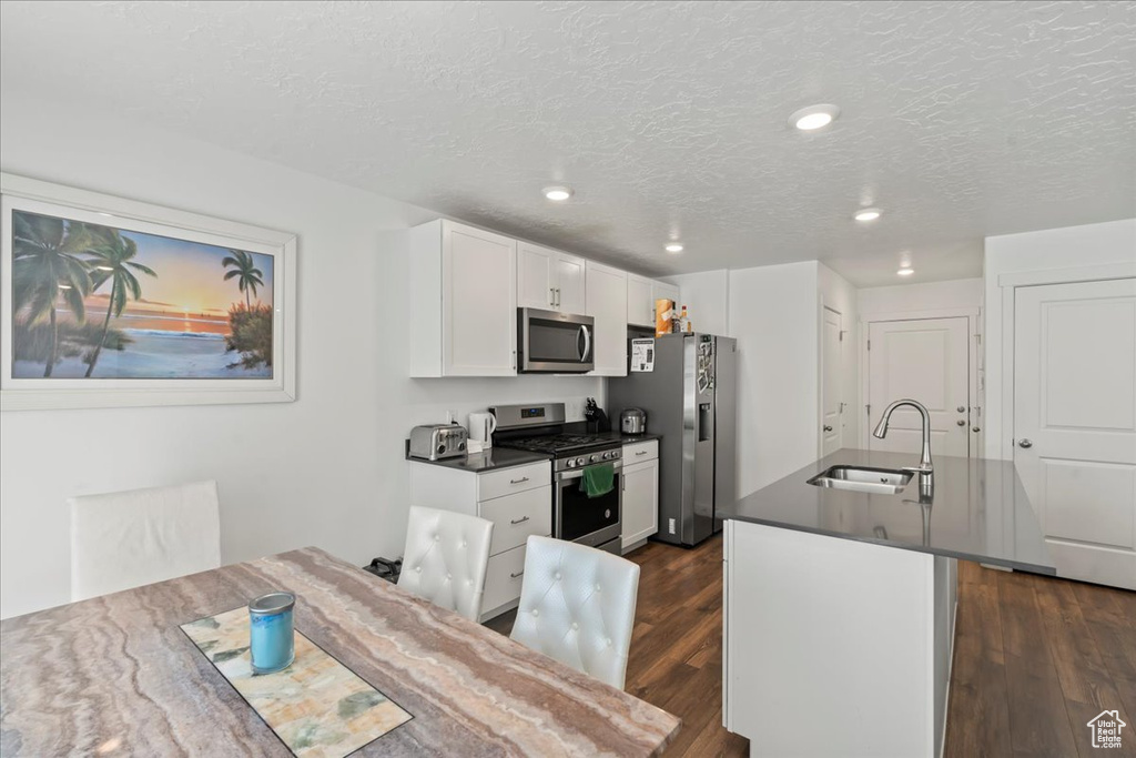 Kitchen featuring appliances with stainless steel finishes, dark wood-type flooring, sink, and white cabinets