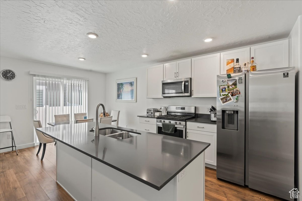 Kitchen featuring appliances with stainless steel finishes, white cabinetry, sink, and dark hardwood / wood-style floors