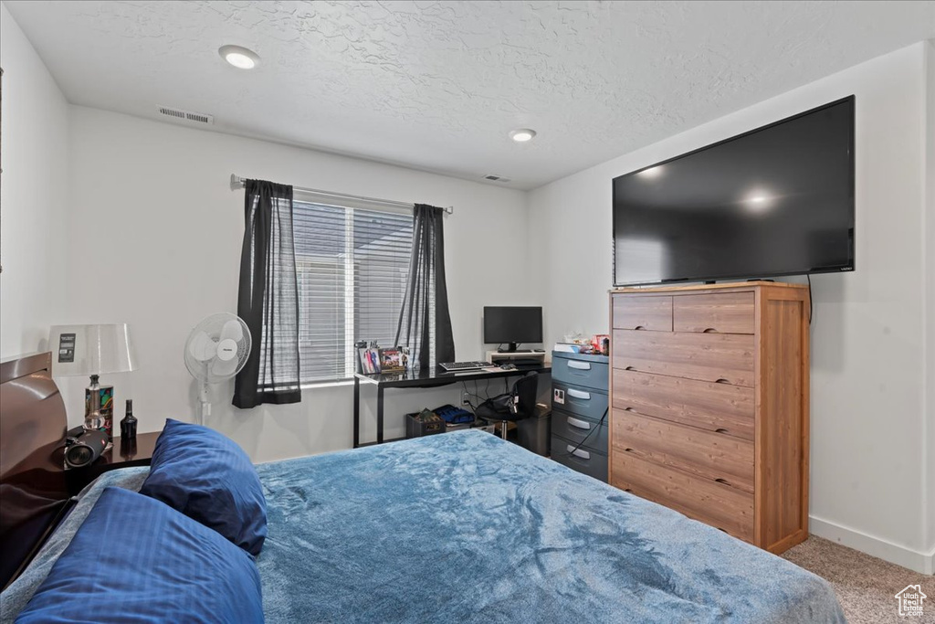 Bedroom with a textured ceiling and carpet