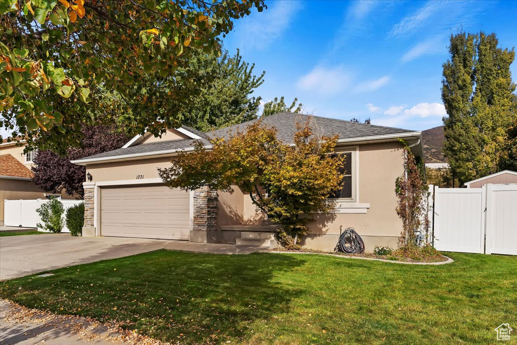 View of property hidden behind natural elements featuring a garage and a front yard