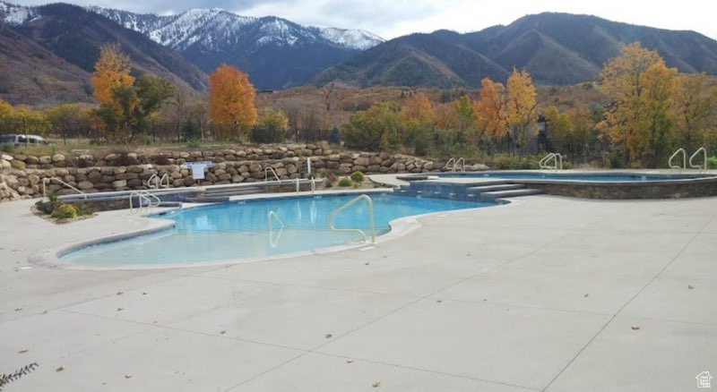 View of swimming pool featuring a mountain view, a hot tub, and a patio area