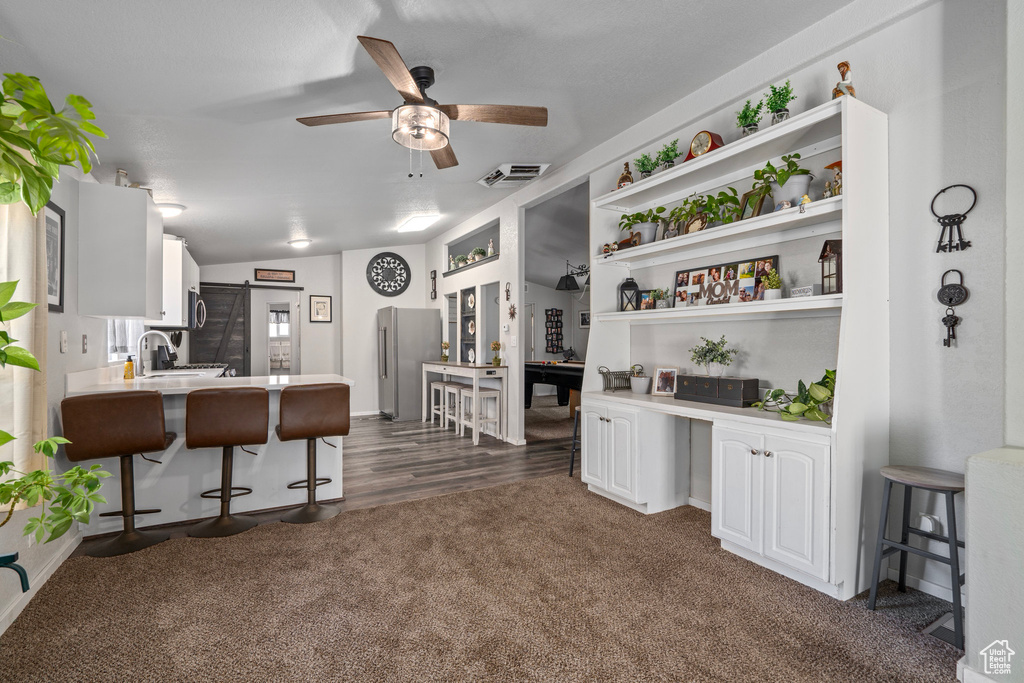 Kitchen featuring kitchen peninsula, white cabinetry, a kitchen breakfast bar, stainless steel appliances, and dark hardwood / wood-style flooring