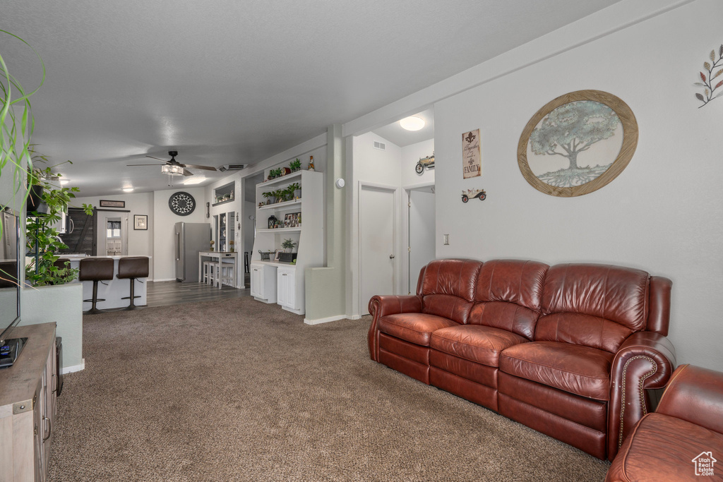 Living room featuring dark carpet and ceiling fan