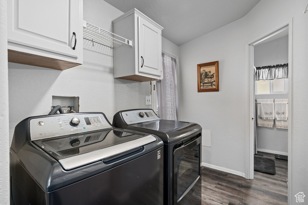 Laundry room with cabinets, dark hardwood / wood-style flooring, and washer and clothes dryer