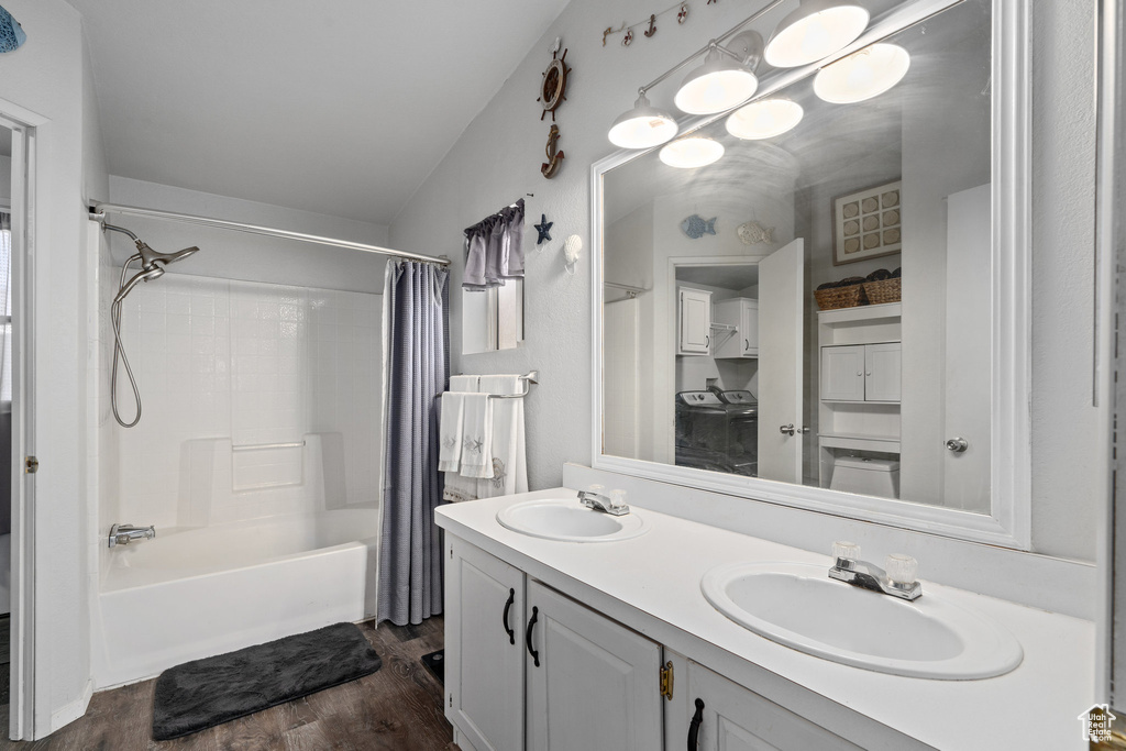 Bathroom with vanity, lofted ceiling, washing machine and clothes dryer, hardwood / wood-style floors, and shower / tub combo with curtain